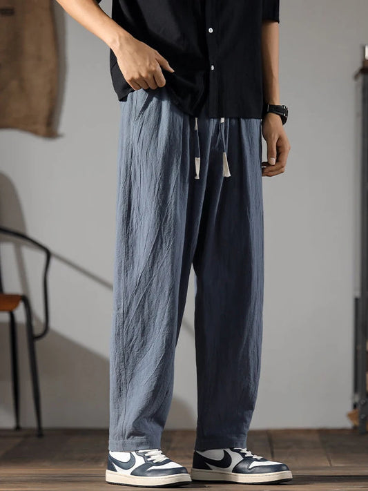 Détail d'un pantalon fluide bleu marine en fibres naturelles, style zen avec cordon de serrage à la taille.