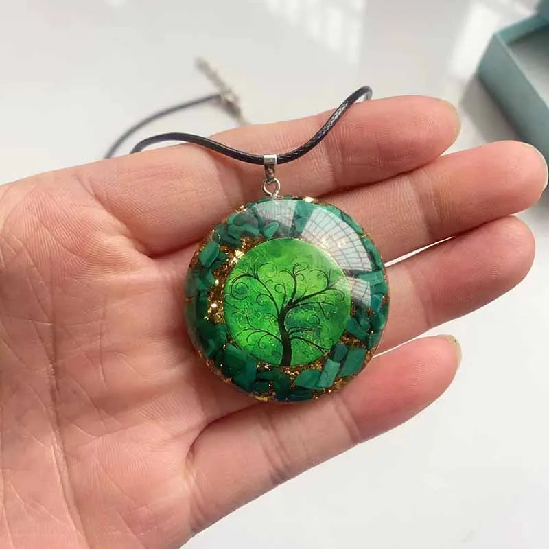 Détail du pendentif orgonite porté en main montrant la transparence de la résine et les pierres de malachite
