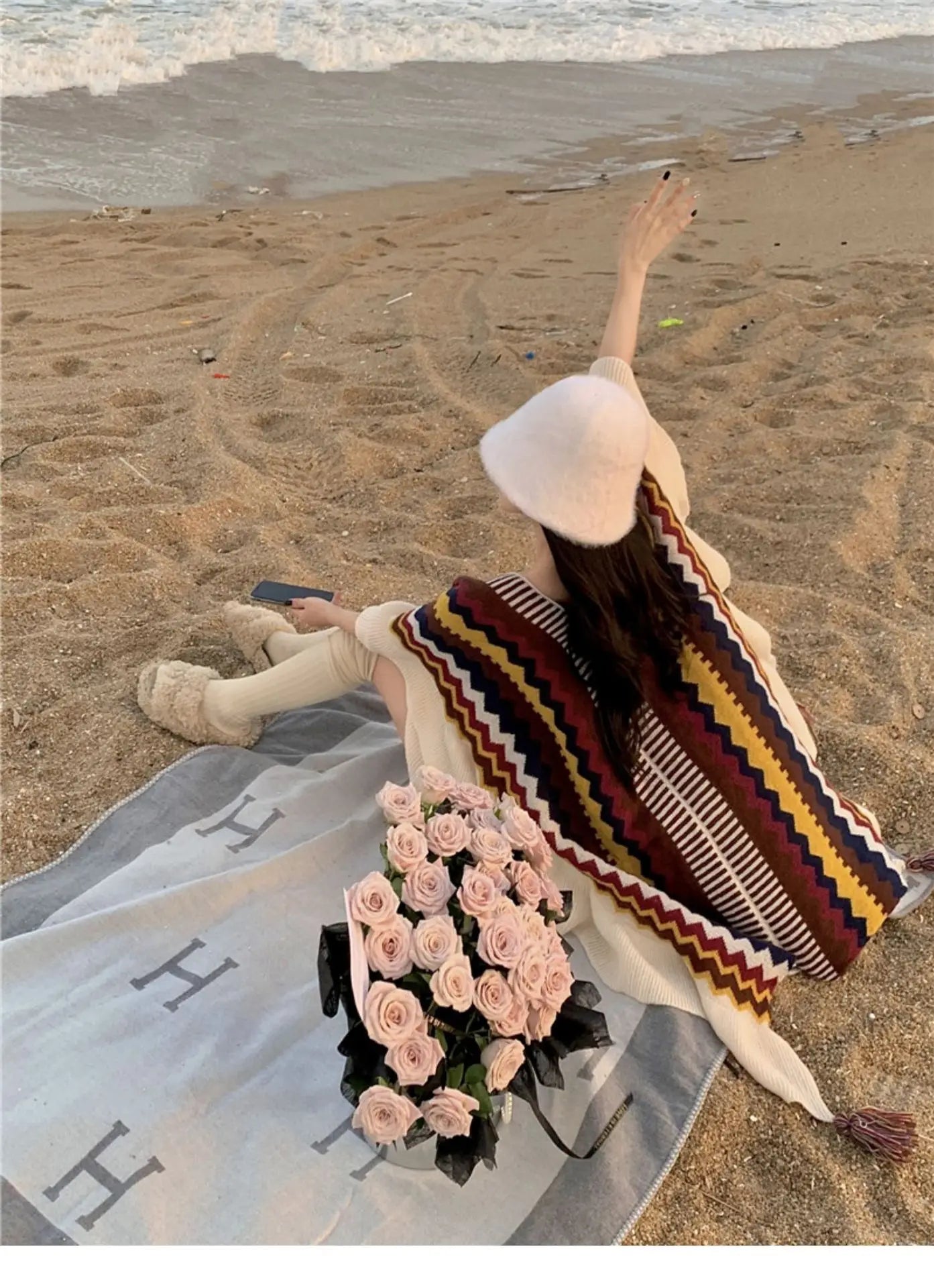 Poncho à rayures rouges et grises, coupe enveloppante avec larges volants en maille écrue.