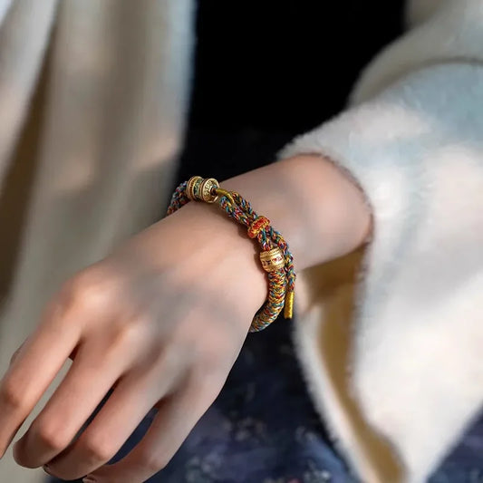 Bracelet bouddhiste artisanal porté au poignet montrant le tressage manuel serré et les détails du mantra protecteur.