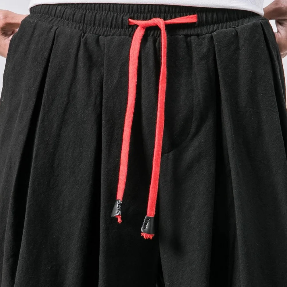 Détail de la taille élastiquée et du cordon de serrage rouge contrasté sur le tissu noir texturé.