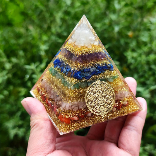 Zoom sur les strates de pierres colorées et les paillettes dorées d'une pyramide d'orgone de 6cm.