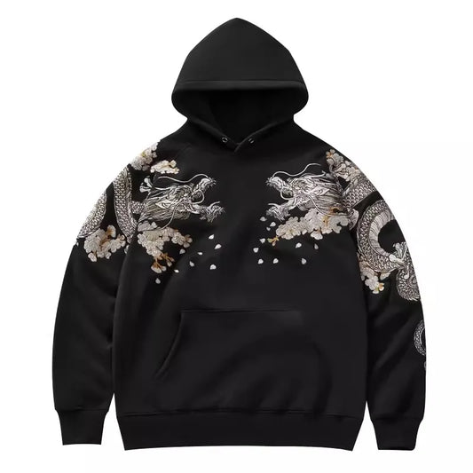 Détail de la face avant du hoodie noir présentant des broderies de dragons symétriques sur le torse et les manches.
