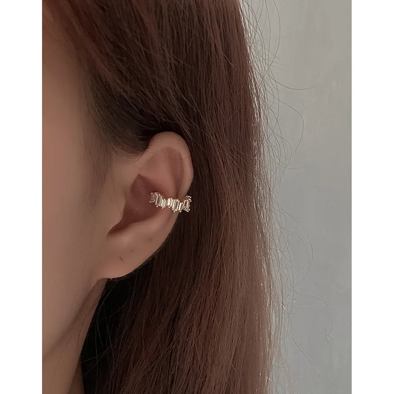 Bague d'oreille dorée ornée de cristaux scintillants, portée avec raffinement sur l'oreille.