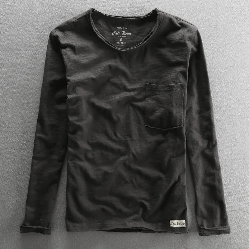T-shirt noir délavé vintage à manches longues, texture coton naturel et poche plaquée sur le devant.