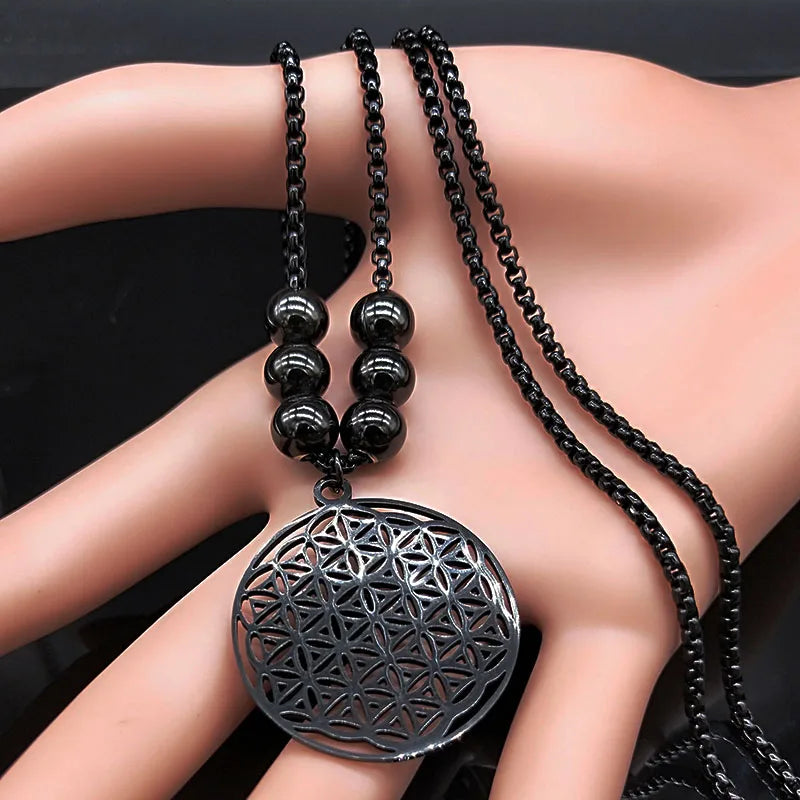 Pendentif Fleur de Vie noir et perles en acier tenus en main pour visualiser la taille.
