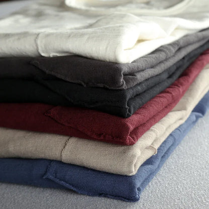 Zoom sur l'étiquette logo cousue au bas du t-shirt bordeaux et la finition de l'ourlet brut.