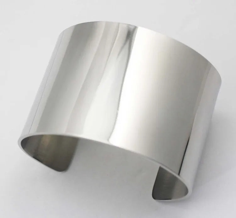 Détail de la finition brossée et des bords arrondis d'un bracelet manchette large en acier inoxydable.