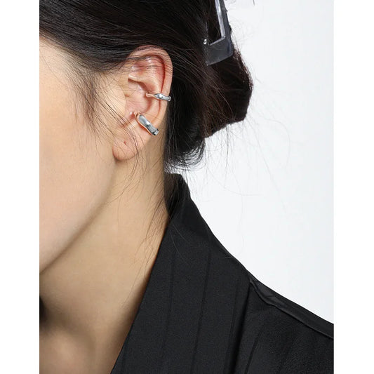 Duo de bagues d'oreille en argent 925 massif au design irrégulier portées sur le cartilage.