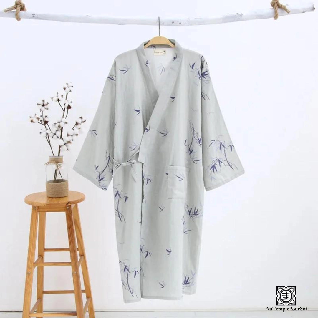 Kimono léger avec motif de branches bleues sur fond gris, évoquant une ambiance zen et tranquille. Présenté de manière artistique avec un décor naturel, parfait pour un confort à la maison ou lors de sorties relaxantes.