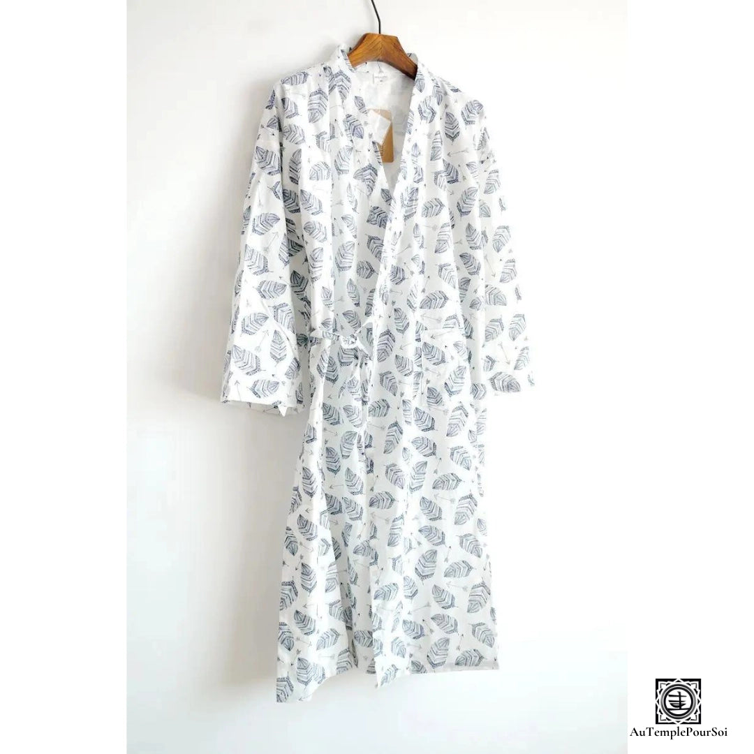 Kimono à motif feuilles graphiques en noir et blanc, suspendu sur un cintre contre un mur blanc, offrant un style naturel et épuré pour une mode détendue et contemporaine.