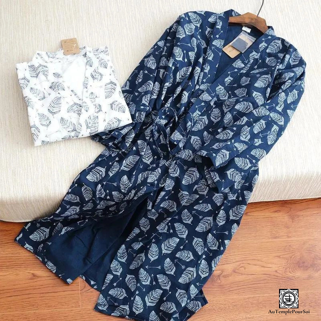 Ensemble de kimonos avec motif feuilles en navy et blanc, affichant un contraste élégant. Le kimono suspendu sur un cintre à côté d'un short plié offre un aperçu du style décontracté et raffiné.