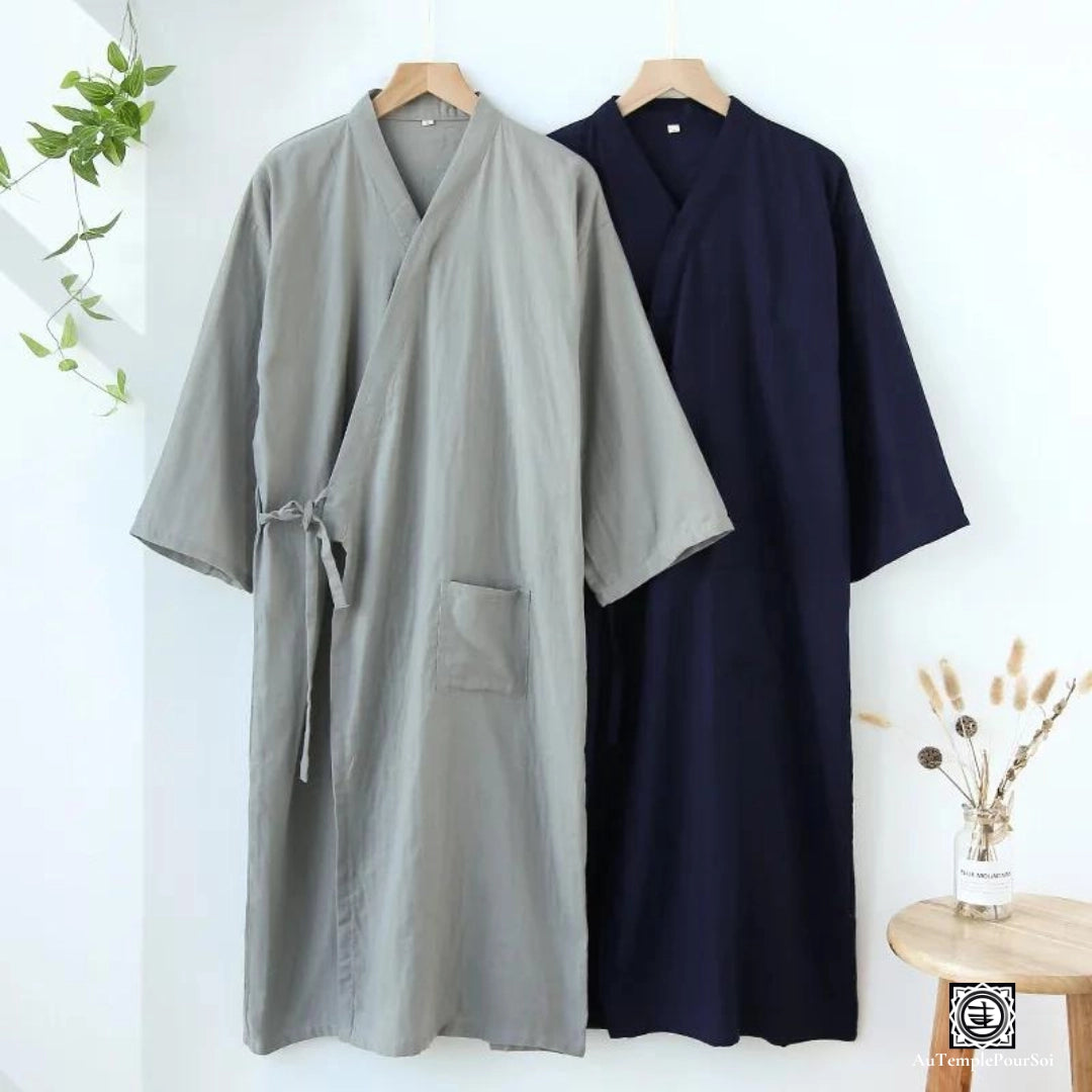 Deux kimonos suspendus côte à côte, l'un en gris doux et l'autre en bleu marine profond, offrant un contraste de couleurs élégant. Leur design simple mais raffiné évoque la tranquillité et la grâce du style traditionnel japonais.