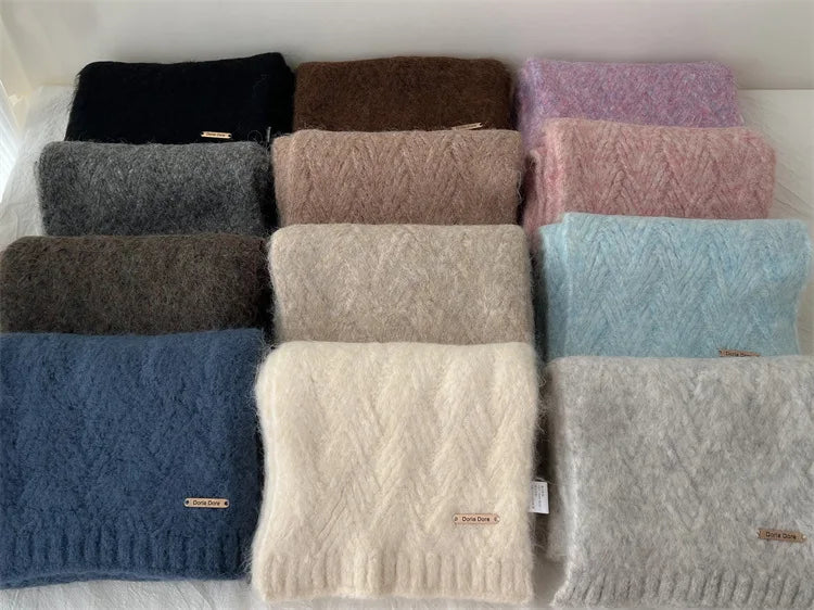 Sélection de onze coloris d'écharpes en grosse maille pliées, allant du beige au bleu marine et rose.