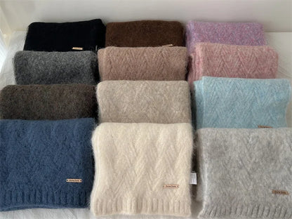 Sélection de onze coloris d'écharpes en grosse maille pliées, allant du beige au bleu marine et rose.