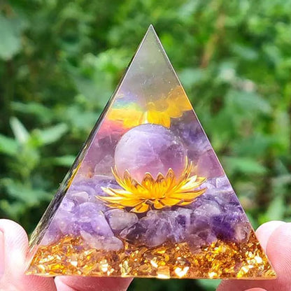 Pyramide d'orgonite en améthyste et obsidienne avec sphère violette et fleur de lotus dorée, vue de face.