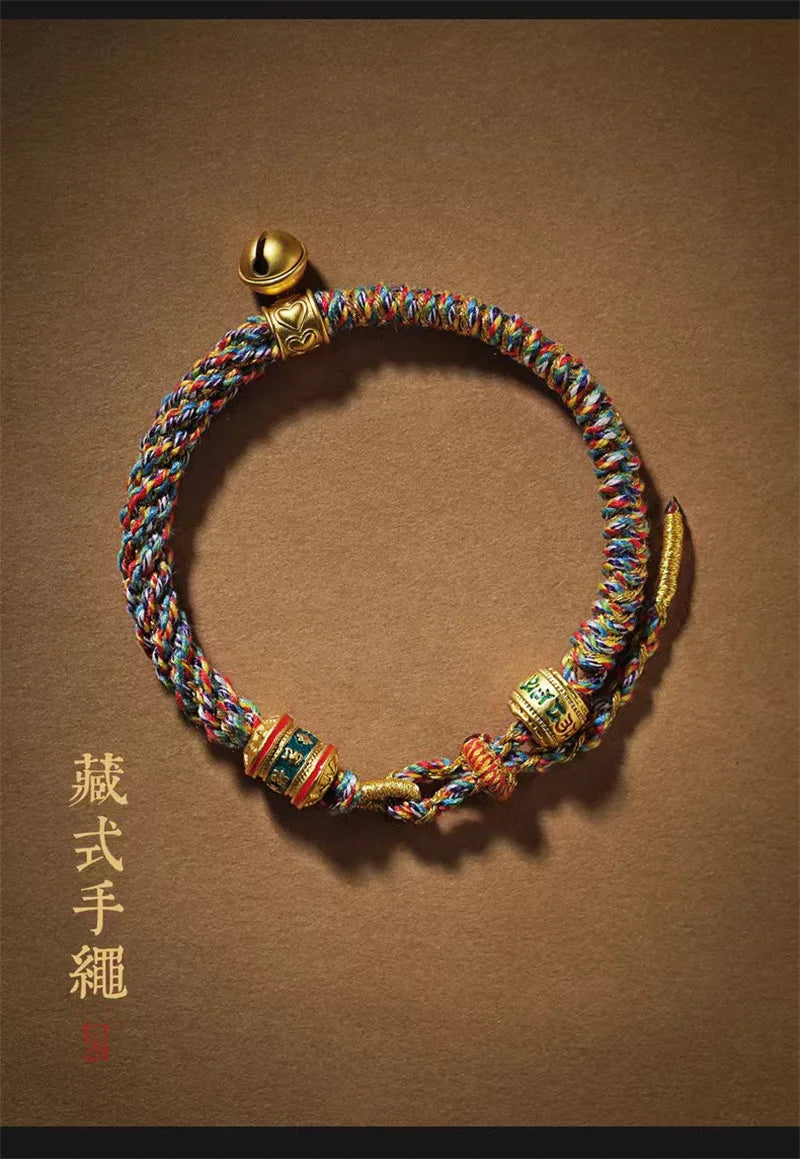 Détail de la petite clochette dorée et du tressage serré du bracelet ethnique.