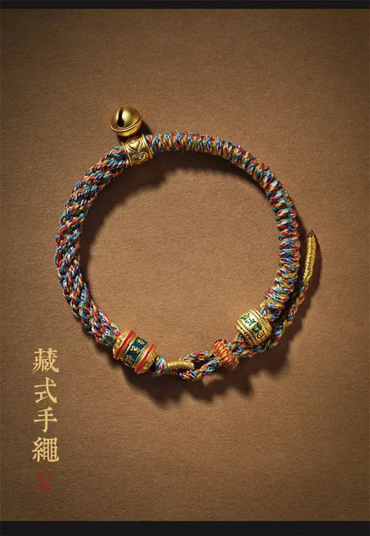 Détail de la petite clochette dorée et du tressage serré du bracelet ethnique.