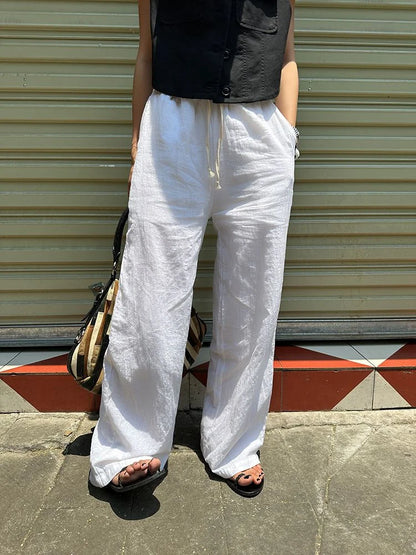 Femme portant le pantalon large en lin blanc fluide en extérieur pour un style zen et décontracté.
