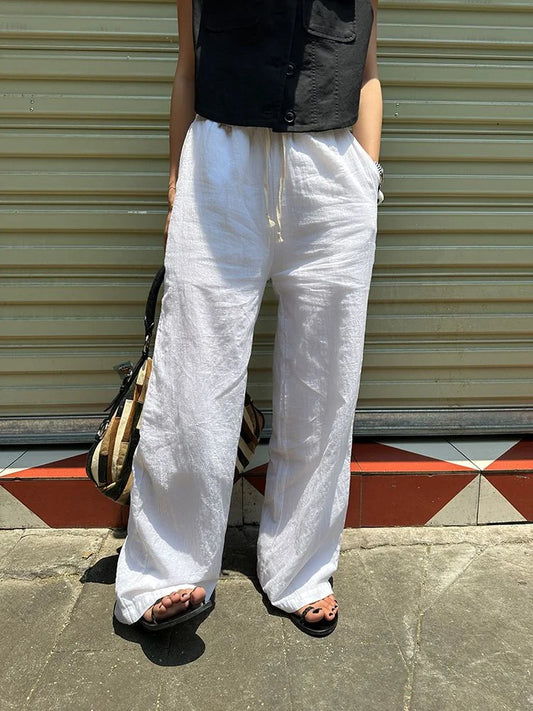 Femme portant le pantalon large en lin blanc fluide en extérieur pour un style zen et décontracté.