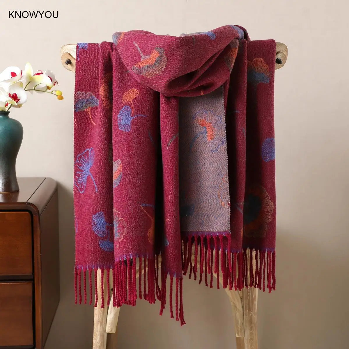 Gros plan sur les franges et la texture ultra-douce d'un pashmina beige fleuri.