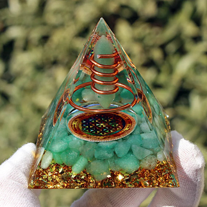 Pyramide d'orgonite en aventurine verte et cuivre avec symbole fleur de vie tenue en main