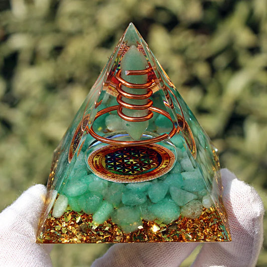 Pyramide d'orgonite en aventurine verte et cuivre avec symbole fleur de vie tenue en main