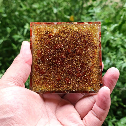 Base de la pyramide d'orgonite montrant la densité des paillettes dorées et des pierres de jaspe rouge.