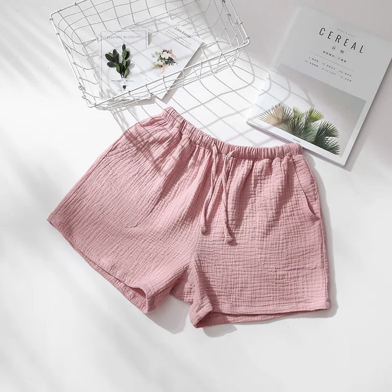 Short de pyjama rose en gaze de coton gaufrée, taille élastique avec cordon de serrage et poches latérales.
