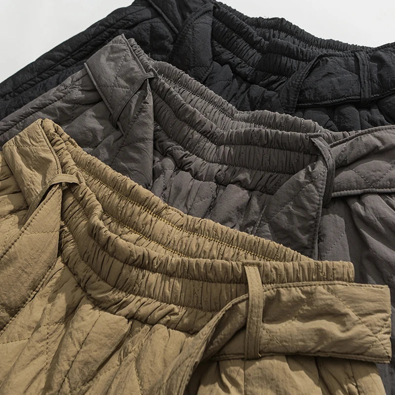 Gros plan sur les tailles élastiquées des sarouels matelassés en noir, gris et kaki.