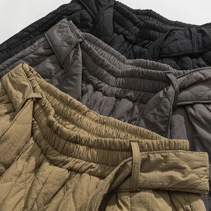 Gros plan sur les tailles élastiquées des sarouels matelassés en noir, gris et kaki.