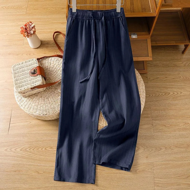 Pantalon zen bleu marine en lin et coton, coupe ample et fluide présentée sur un fond en bois clair.