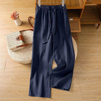 Pantalon zen bleu marine en lin et coton, coupe ample et fluide présentée sur un fond en bois clair.