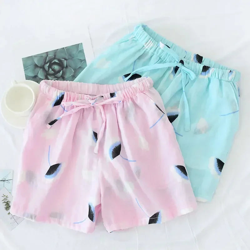Duo de shorts de pyjama rose et bleu en double gaze de coton avec motifs de pétales noirs et bleus.