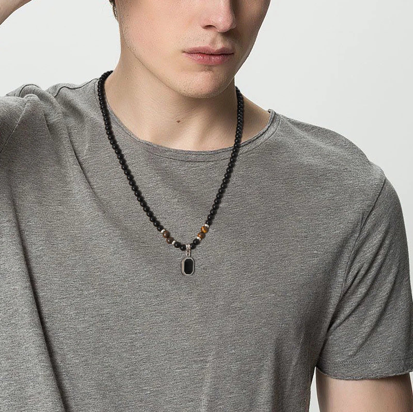 Détail macro des reflets dorés des perles œil de tigre contrastant avec les perles noires lisses du collier.