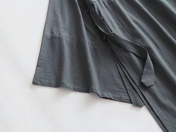 Cardigan ample noir suspendu sur cintre, montrant la fluidité du tissu en lin et coton.