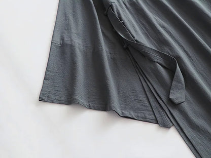 Cardigan ample noir suspendu sur cintre, montrant la fluidité du tissu en lin et coton.