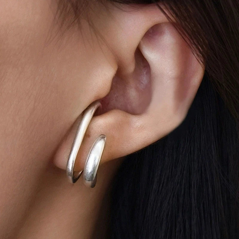 Zoom sur la bague d'oreille double cercle en argent au style vintage épuré.