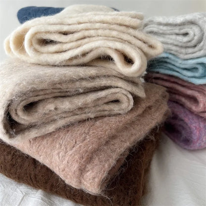 Gros plan sur le tissage d'écharpes en laine crème et beige, mettant en relief la douceur des fibres.