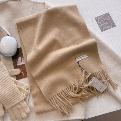 Écharpe longue beige disposée à plat avec gants assortis et accessoires d'hiver.