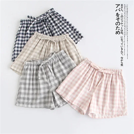 Vue d'ensemble de quatre shorts de pyjama en gaze de coton à carreaux coloris rose, gris, beige et bleu marine.