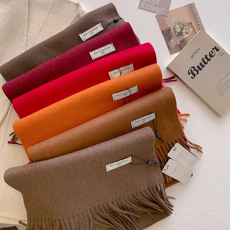 Pile d'écharpes en laine aux tons chauds bordeaux orange et marron avec étiquettes de composition