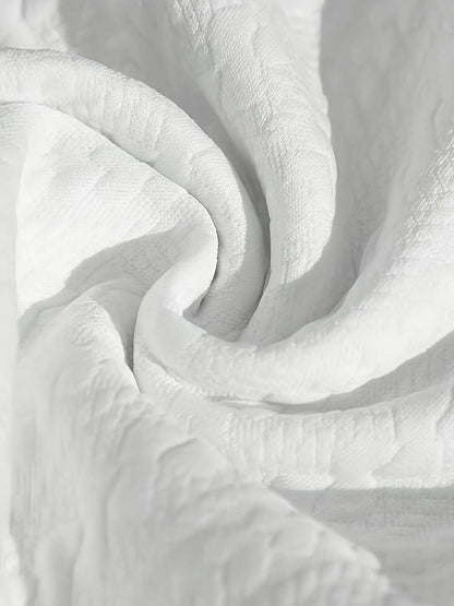 Détail du tissu blanc drapé montrant la souplesse et le relief du tissage jacquard texturé de haute qualité.