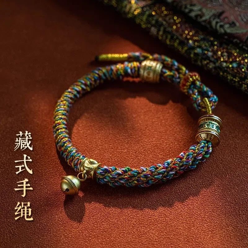 Bracelet tibétain en corde tressée multicolore avec perles dorées gravées du mantra Om Mani Padme Hum et clochette.