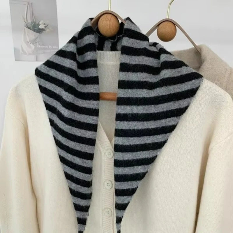 Foulard en laine à rayures grises et noires, porté ouvert sur les épaules d'un cardigan.