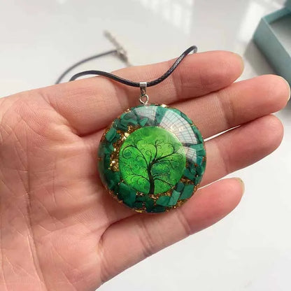Détail du pendentif orgonite porté en main montrant la transparence de la résine et les pierres de malachite