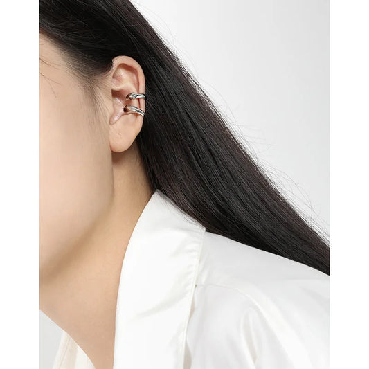 Femme portant deux bagues d'oreille en argent 925 au design irrégulier, style minimaliste sans perçage.