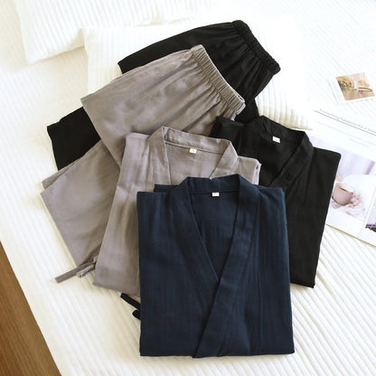 Détail des ensembles de nuit kimono pliés sur un lit, montrant la texture douce du coton et le col en V.