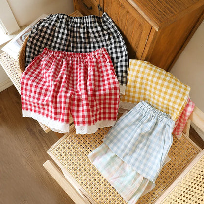 Sélection de shorts de pyjama vichy en gaze de coton : coloris rouge, noir, jaune et bleu sur une chaise.