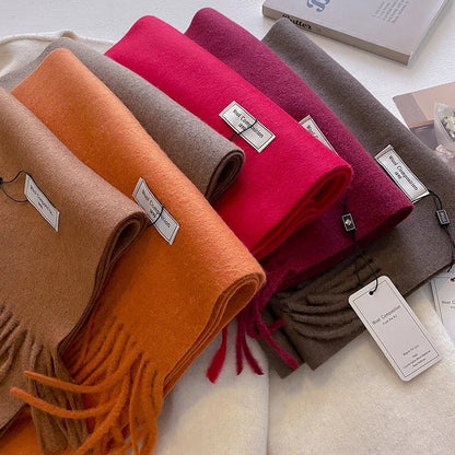 Pile d'écharpes en laine colorées (orange, rouge, marron) avec étiquettes de composition.